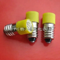 Set of three LED bulbs 220v/240v with E10 base and yellow ribbed caps on red background